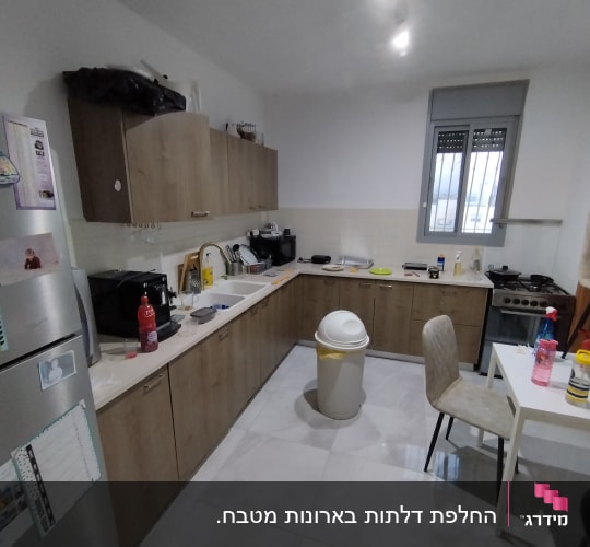 מטבח עם ארונות עץ, כיור, תנור וכלים על השיש